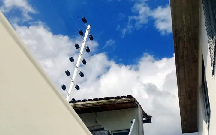Haste de cerca elétrica com isoladores instalada em muro residencial
